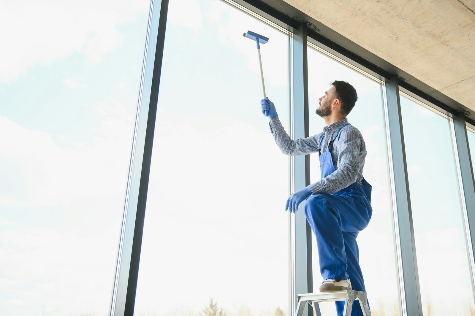 Young man cleaning window in office