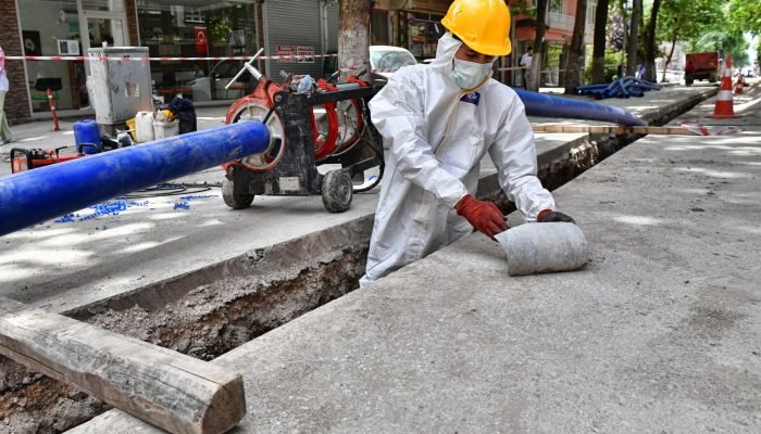 a man wearing a protective suit and a hard hat working on a street