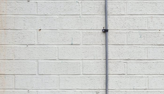 a red fire hydrant in front of a white brick wall